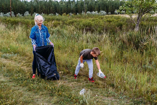Женщина и семилетний мальчик положили мусор в мешок — стоковое фото