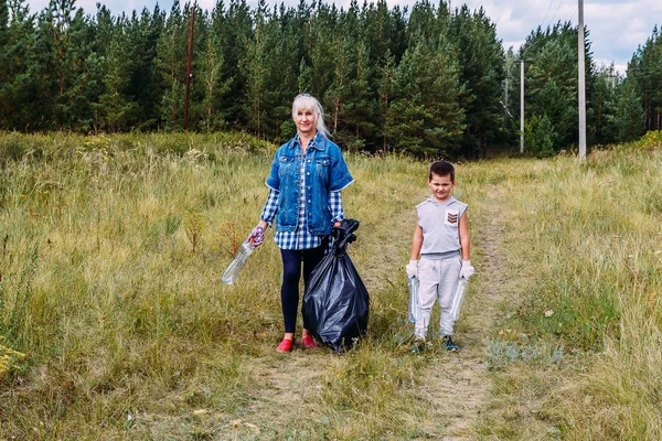 Бабушка и внук идут с большим мешком для мусора в природе — стоковое фото