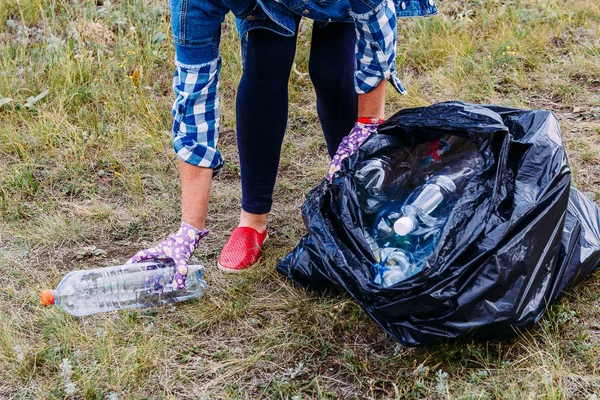 Женщина в джинсовой куртке очищает окружающую среду от пластиковых отходов . — стоковое фото