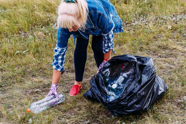 Woman collects plastic trash in a bag