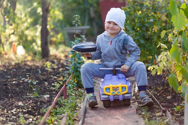 Мальчик едет на детской машине в сад — стоковое фото