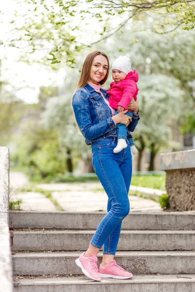 Leende Kvinna Lång Jeansdräkt Håller Liten Flicka Armarna Utomhus — Stockfoto