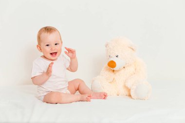 Gülümseyen bebek ve beyaz arka planda yumuşak oyuncak ayı