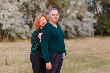 Bir kadın yazın bir erkeğe sarılır. Orta yaşlı karı koca dışarıda.