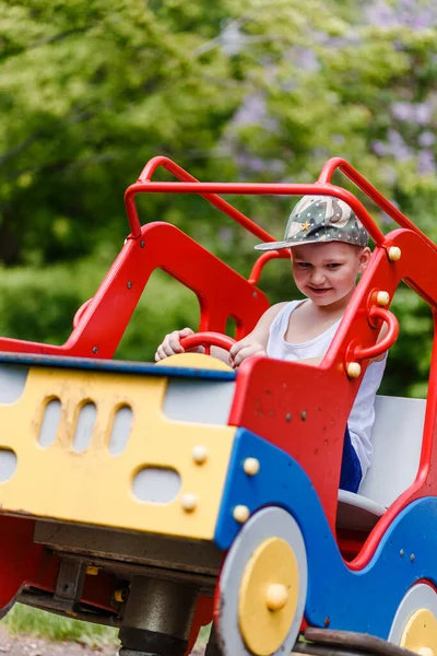 Yedi yaşında bir çocuk yazın çocuk arabası sedyesine biniyor.