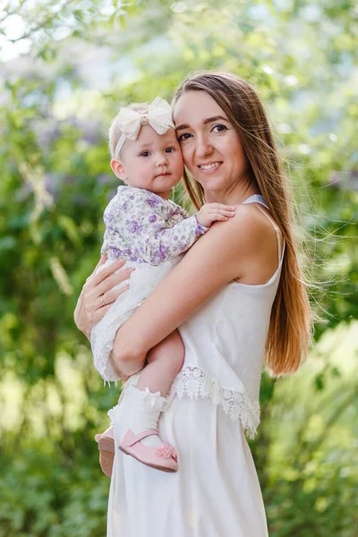 一个快乐的微笑的母亲在模糊的背景下拥抱了一个10个月大的女婴 母亲和女儿 — 图库照片