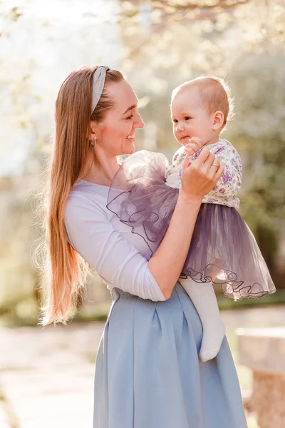 Leende Trettioårig Kvinna Håller Vacker Liten Flicka Klänning Suddig Bakgrund — Stockfoto