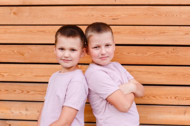 İki yakışıklı çocuk, tahta bir arka planda kameraya bakıyor.