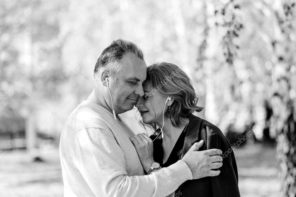 middle-aged man and woman with headphones.a man gently hugs his wife.black white photo