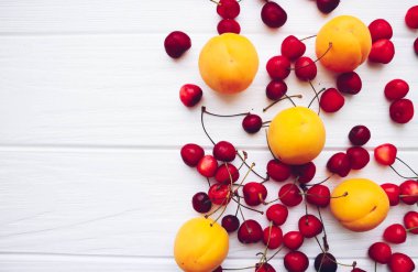 Beyaz ahşap arka planda kayısı ve kirazlar