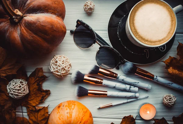 Stylish flatlay arrangement with coffee, brushes, candles, phone and other stationary accessories.