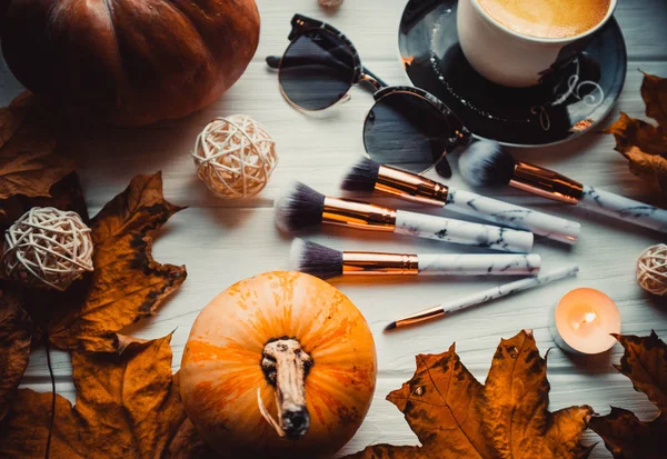 Stylish flatlay arrangement with coffee, brushes, candles, phone and other stationary accessories.