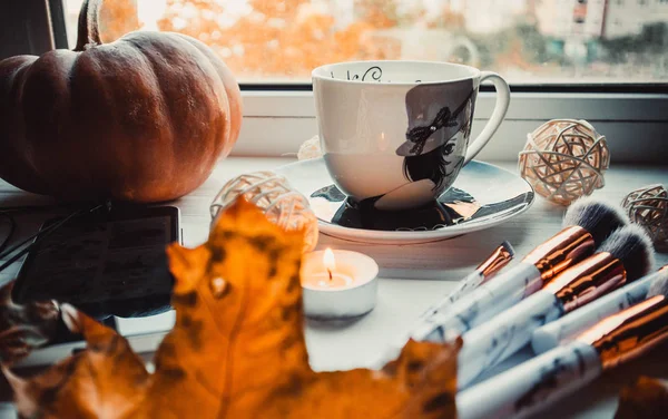 Stylish flatlay arrangement with coffee, brushes, candles, phone and other stationary accessories.