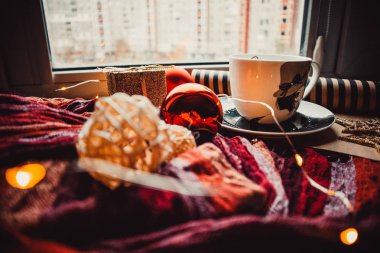 Ahşap arka planda bir fincan kahve, içinde Noel oyuncakları ve kağıt var.