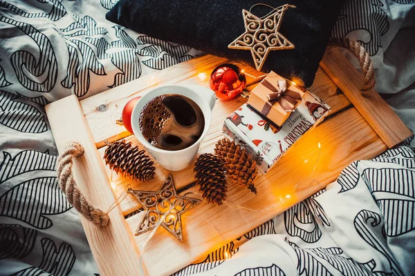 Tahta tepside bir fincan kahve ve Noel oyuncakları.