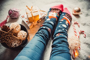 Arkaplanda dişi bacaklar, rahat ve sıcak bir ekose ve Noel süslemeleri.