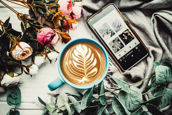 Ahşap Beyaz Arka Planda Çiçekli Bir Fincan Kahve Telefon — Stok fotoğraf