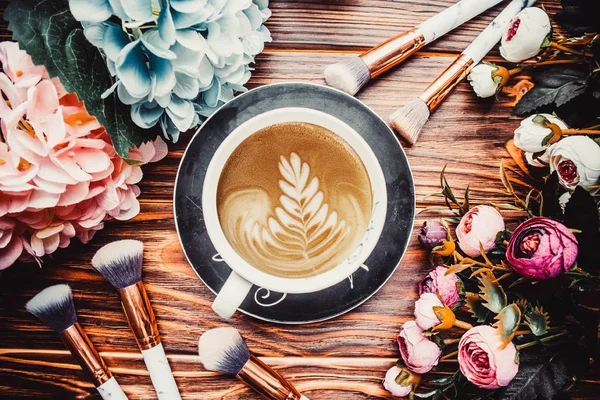 Cup Kaffe Trä Brun Bakgrund Med Blommor Och Sminkborstar — Stockfoto