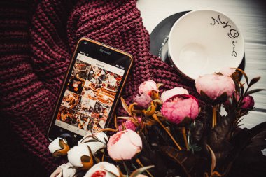 Yumuşak süveter ve beyaz ahşap arka planda telefon ve fincan