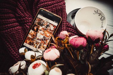 Yumuşak süveter ve beyaz ahşap arka planda telefon ve fincan