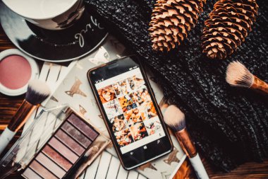 Telefon, not defterleri ve tahta bir arka planda örülmüş süveter.