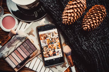 Telefon, not defterleri ve tahta bir arka planda örülmüş süveter.