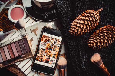 Telefon, not defterleri ve tahta bir arka planda örülmüş süveter.