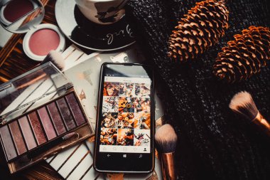 Telefon, not defterleri ve tahta bir arka planda örülmüş süveter.