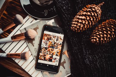 Yumuşak süveter ve beyaz ahşap arka planda telefon ve fincan