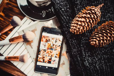 Yumuşak süveter ve beyaz ahşap arka planda telefon ve fincan