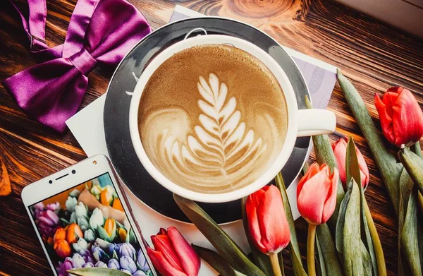 Kahverengi Arka Planda Bir Fincan Kahve Telefon Çiçekler — Stok fotoğraf