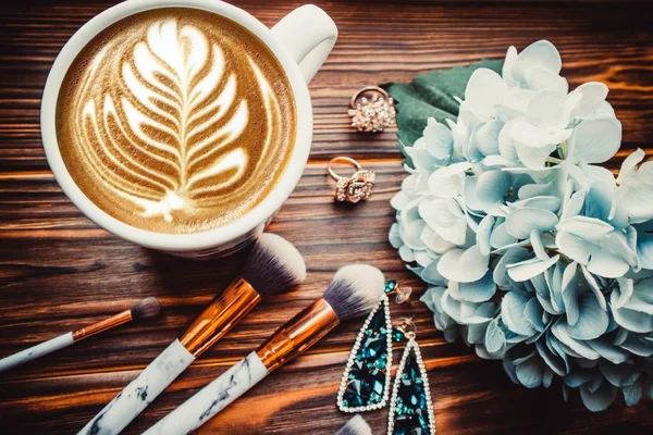Bir Fincan Kahve Makyaj Fırçaları Tahta Bir Arka Planda Çiçekler — Stok fotoğraf