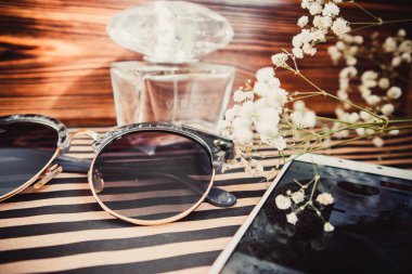 Güneş gözlüğü, cep telefonu ve parfüm ahşap arka plan üzerinde