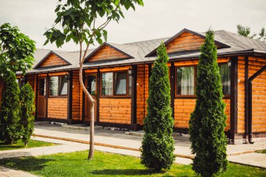 Ağaçların ve çimenlerin arkasındaki güzel ahşap evler. Kiev 'deki restoranın yaz terası..