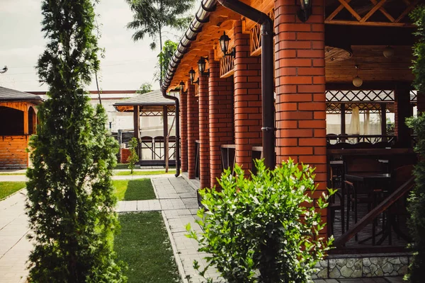 Ağaçların ve çimenlerin arkasındaki güzel ahşap evler. Kiev 'deki restoranın yaz terası..