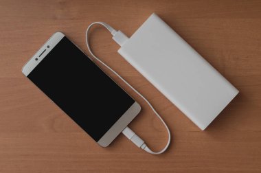 Modern bir akıllı telefon ve ahşap arka plan üzerinde bağlı güç banka.