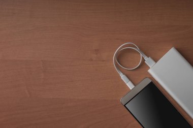 Modern bir akıllı telefon ve ahşap arka plan üzerinde bağlı güç banka.