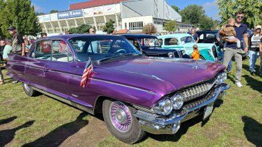 Breclav, Çek Cumhuriyeti - 9 Eylül 2025, Cadillac DeVille şatosu altındaki Veteranlar tarihi araba gösterisi. Kaputunda kırmızı, beyaz ve mavi bayrak olan mor bir araba..