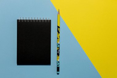 Mavi ve sarı arka planda not defteri ve kalem