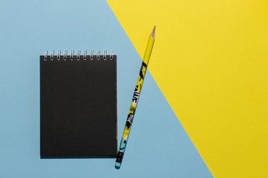 Mavi ve sarı arka planda not defteri ve kalem