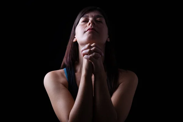 接近一个忠实的妇女祈祷 双手折叠在崇拜 抬头和闭着眼睛在宗教狂热 在黑色背景 祈祷和灵性的概念 — 图库照片
