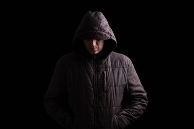 Scary and creepy man hiding in the shadows, with the face and identity hidden with the hood, and standing in the darkness. Low key, black background. Concept for fear, mystery, danger, crime, stalker clipart