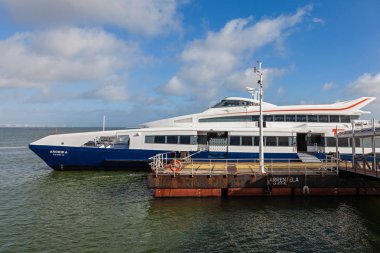 Seixal, Portugal - October 24, 2016: Modern ferry with catamaran hull, waiting for passengers on the Seixal Ferry Terminal to transport the commuters to Lisbon. Built by FBM Marine for Transtejo clipart