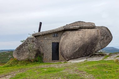 Casa do Penedo, a house built between huge rocks on top of a mountain in Fafe, Portugal. Commonly considered one of the strangest houses in the world. clipart