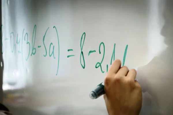 Lise eğitiminde, el Yeşil işareti ile matematik formülü bir beyaz tahta üzerinde yazıyor