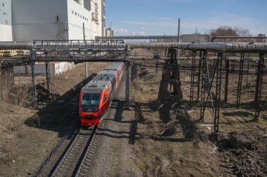 Banliyö kırmızı treni sanayi bölgesinden geçiyor. Yukarıdan görüntüle.