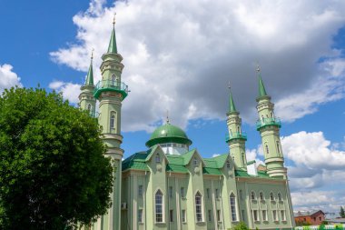 Mavi gökyüzüne karşı yeşil kubbeli cami.
