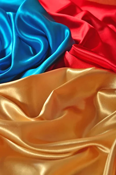 Natural golden, blue and red satin fabric as background texture