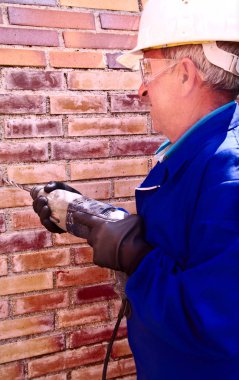 Dikey yakın tuğla bir duvar delme kask, eldiven ve iş gözlüğü, eski dostum,