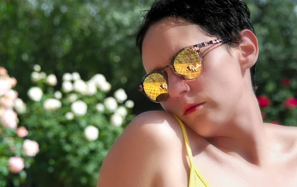 Sad black hair woman, looking at her right side, wearing yellow shirt, in a garden of white roses, at the right side of the picture